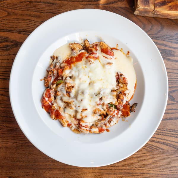 Chicken fajitas with melted cheese and red sauce on a white plate.